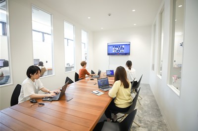 会議室のモニターでオンライン会議をする女性スタッフたち