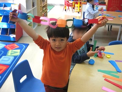 折り紙の輪飾りを披露する少年