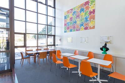 白い机とオレンジの椅子が並び開放的な窓が特徴のHISのロビー