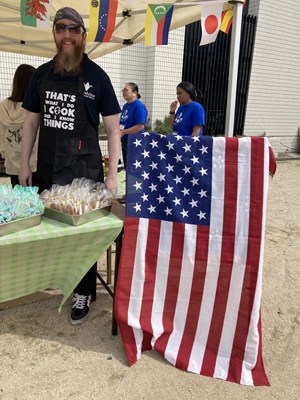 グルメブースにてアメリカ国旗の横に立つ男性