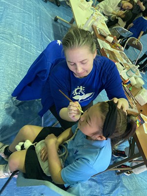 外国人女性が女の子にフェイスペイントをしている