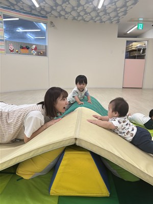 乳幼児クラスの児童と先生がマットで顔を見合わせている