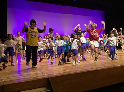 ステージで踊る講師と児童たち