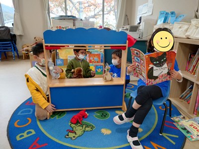 教室で絵本を読んであげる女の子とクラスメイト