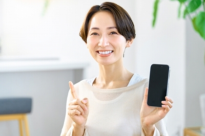 スマホを片手に指を差す女性
