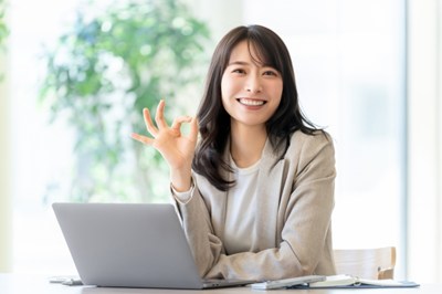 パソコンの前でOKポーズをする女性