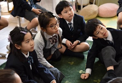 床に座って話を聞く子ども