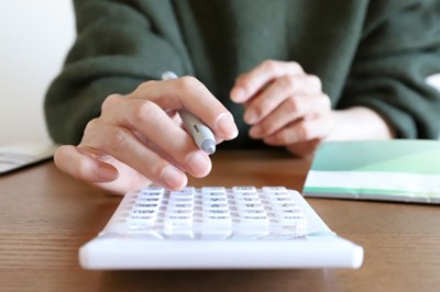 電卓でお金の計算をする女性の手元