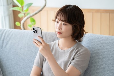 ソファでスマホを見る女性