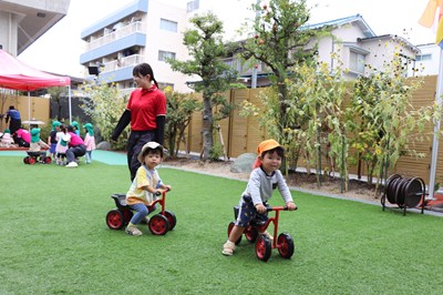 三輪車に乗る乳幼児クラスの子どもたち