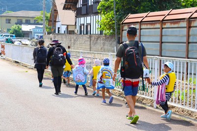子どもたちと先生が歩いて川に向かう様子