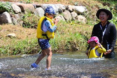 川遊びを楽しむ子どもたちと先生の姿