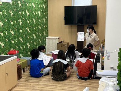 床に座って歯科衛生士の話を聞く小学生