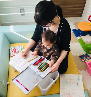 小さな子どもと塗り絵をする保育士