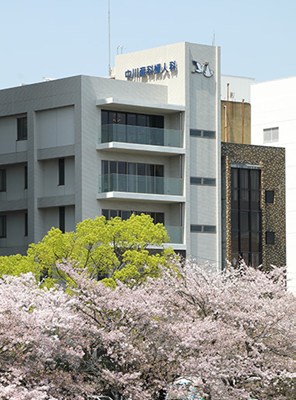 ALT=桜並木越しに見える中川産科婦人科の外観