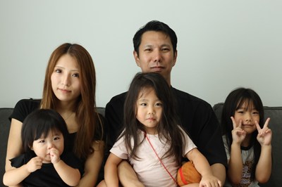 ソファに座る夫婦と幼い3姉妹の5人家族