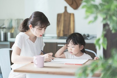 家庭で机に向かう女の子と母親