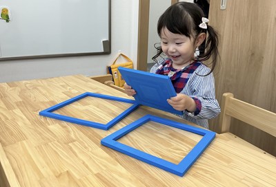 青い正方形枠の教具で遊ぶ女の子