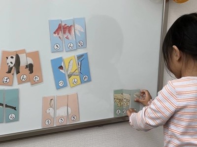 ホワイトボードにカードの教具を貼る女の子