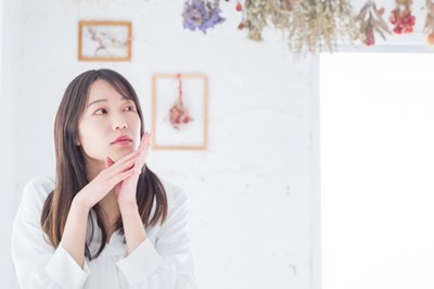 女性が頬に手を当てて考え事をしている様子