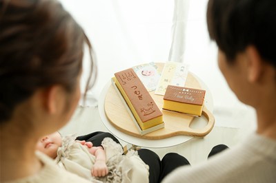 赤ちゃんと家族が名入れカステラなどのギフト商品を見つめている様子