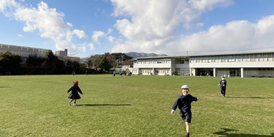 青空のもと、広い校庭を元気に駆け回る子どもたち